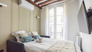 Ein Schlafzimmer mit einem Bett, einem Fenster und einem an der Wand befestigten Fernseher.