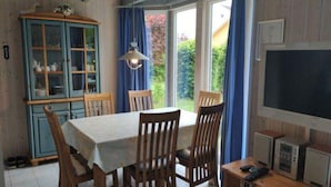 A dining area with a table, chairs, a cabinet, and a television.