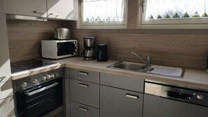 A compact kitchen with a microwave, coffee maker, and sink.