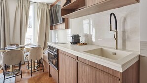 A modern kitchen with wooden cabinets, a white countertop, and a black faucet. - New Apartment Center of Paris/le Marais (Paris)