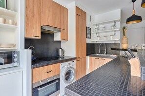 Eine moderne Küche mit Holzausstattung, einer integrierten Waschmaschine und einer Mikrowelle.