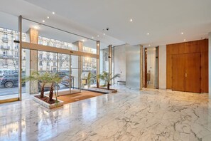 Eine moderne Hotelhalle mit Marmorböden, großen Glastüren und Holztüren.