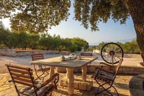An outdoor dining area with a table and chairs, surrounded by trees and a view of distant mountains. - Charming Villa With Swimming Pool (Pucisca)