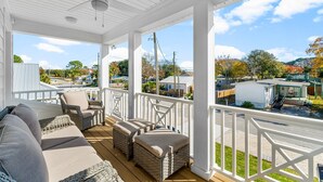 A covered porch with wicker furniture and a view of a residential area. - BRAND NEW CONSTRUCTION! CLOSE TO BEACH!  PET FRIENDLY! 3/2 SLEEPS 6! (Panama City Beach)