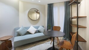 A modern living room with a sofa, a round table, and a mirror. - Modern Suite Center of Paris Montmartre (Paris)