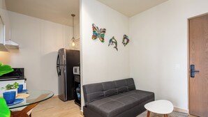 A compact living space with a sofa, a small table, and a refrigerator.