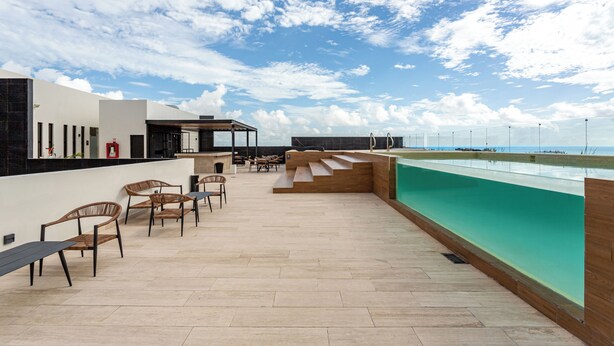 A rooftop terrace with a pool, outdoor seating, and a clear view of the sky.