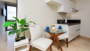 A modern kitchen with white cabinets, a black countertop, and a glass dining table with chairs.