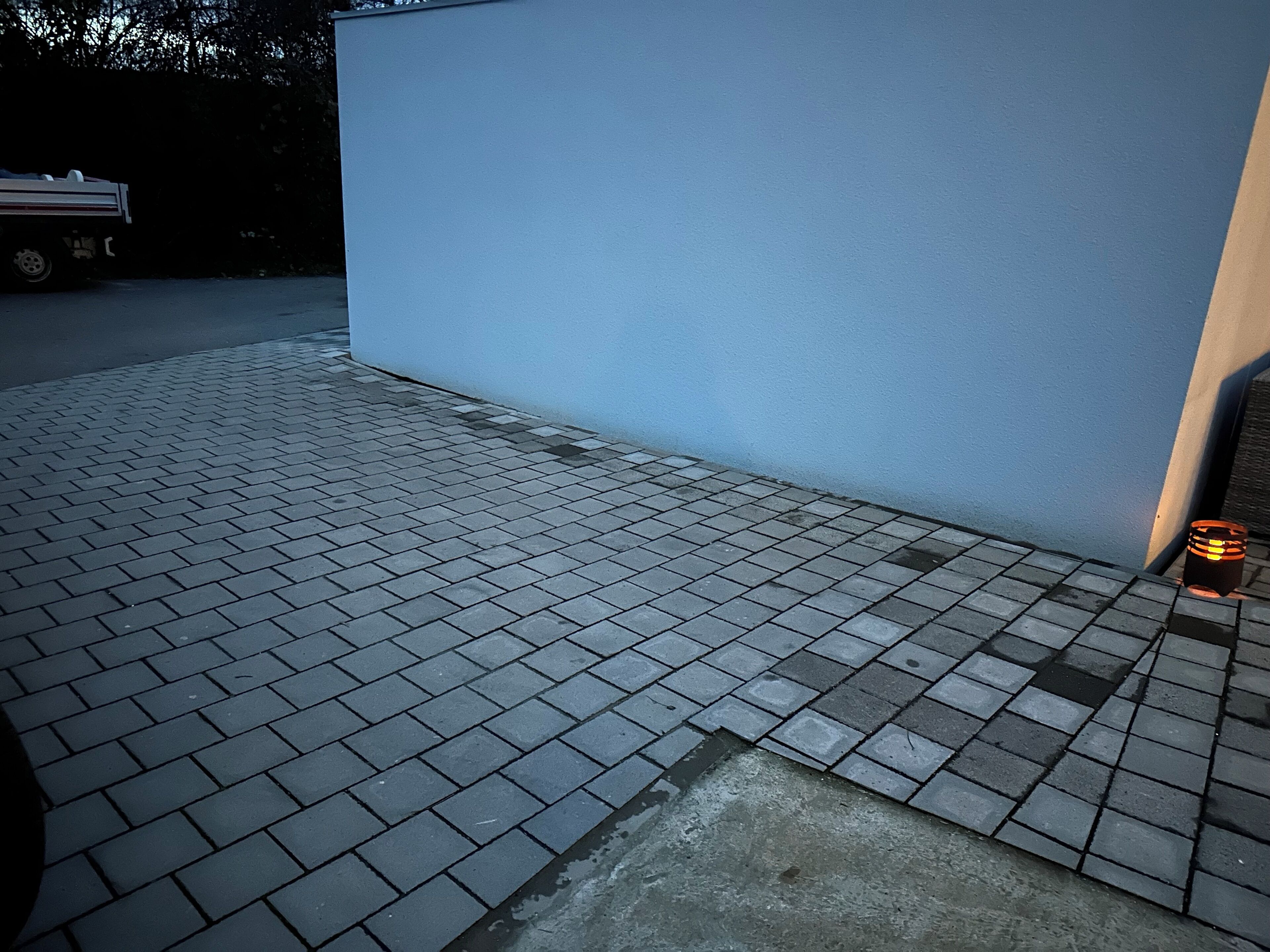 Ein gepflasterter Außenbereich mit einer blauen Wand und einem kleinen, orangefarbenen Gegenstand in der Nähe.