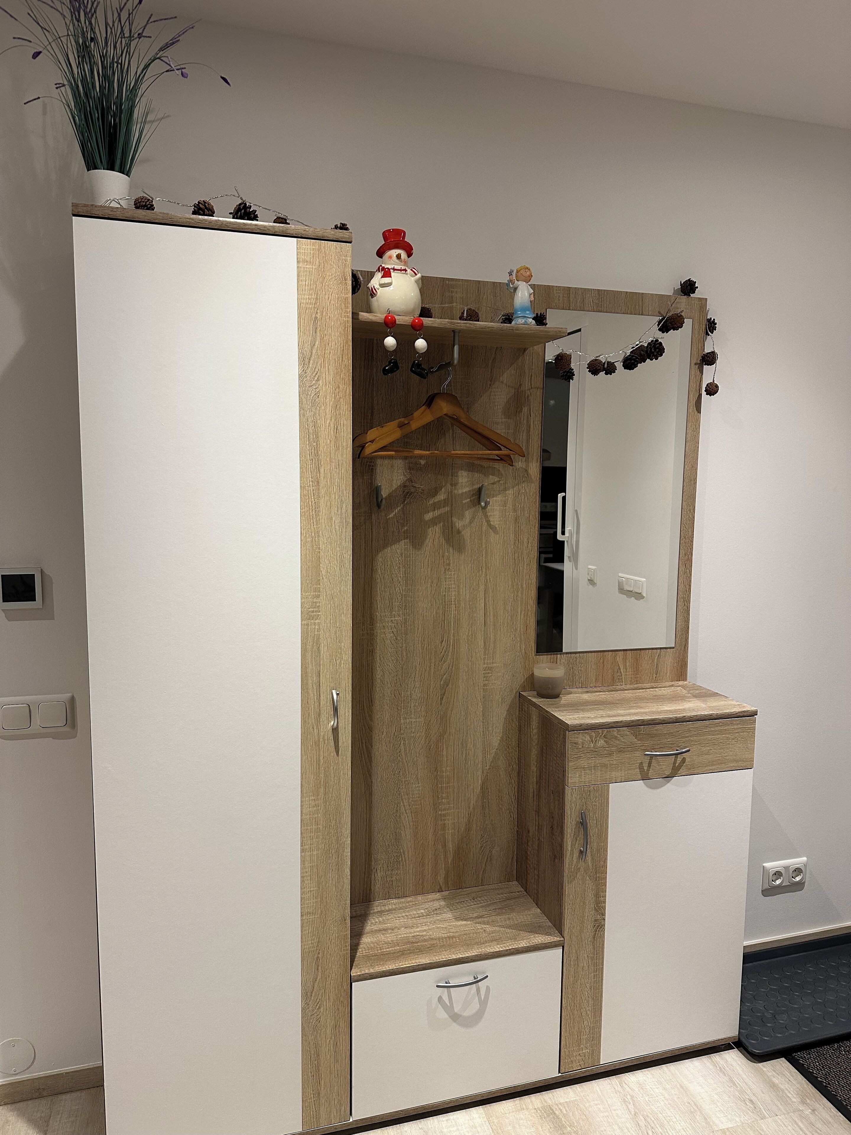 A wardrobe with a mirror, wooden paneling, and a small shelf with decorative items.