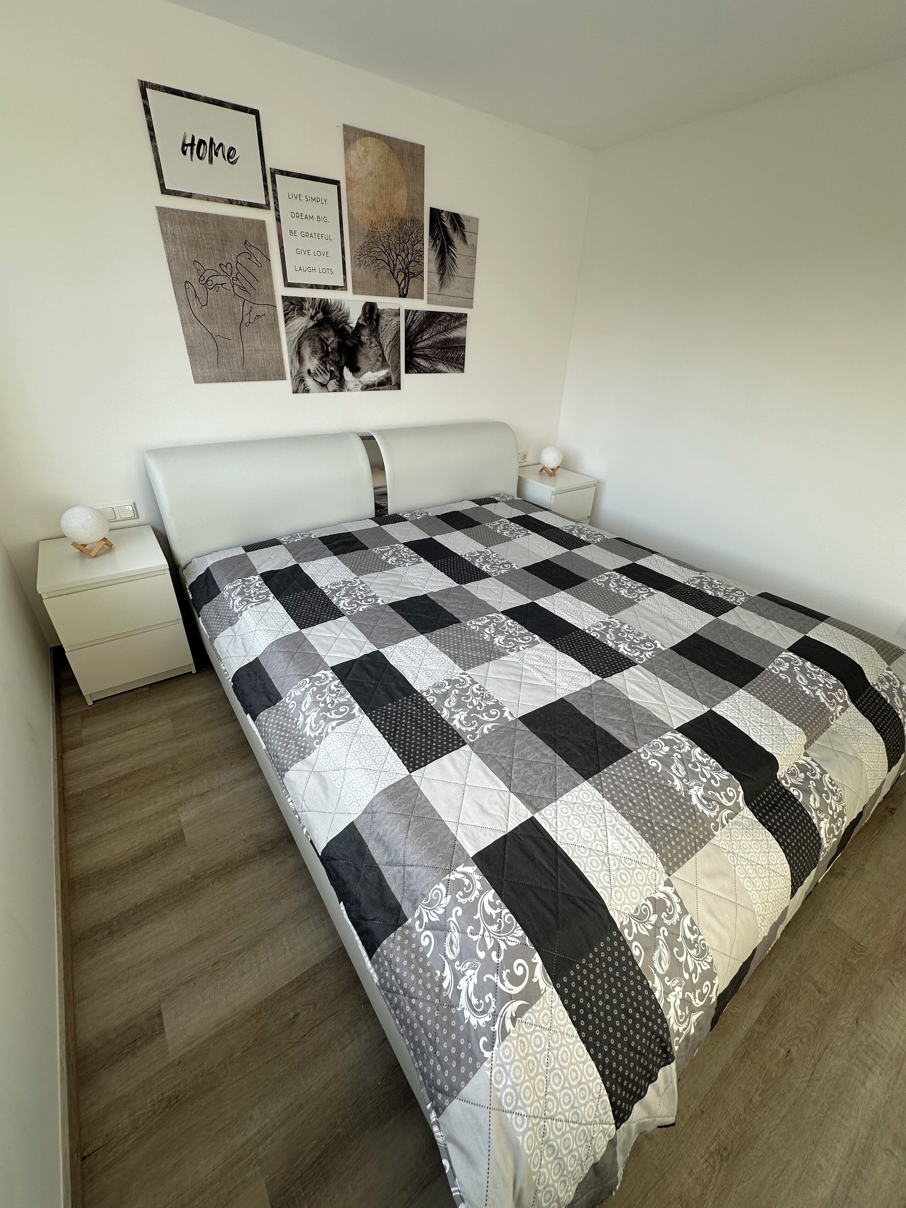 Une chambre avec un grand lit, une table de chevet, une horloge murale et des œuvres d’art motivantes accrochées au mur.
