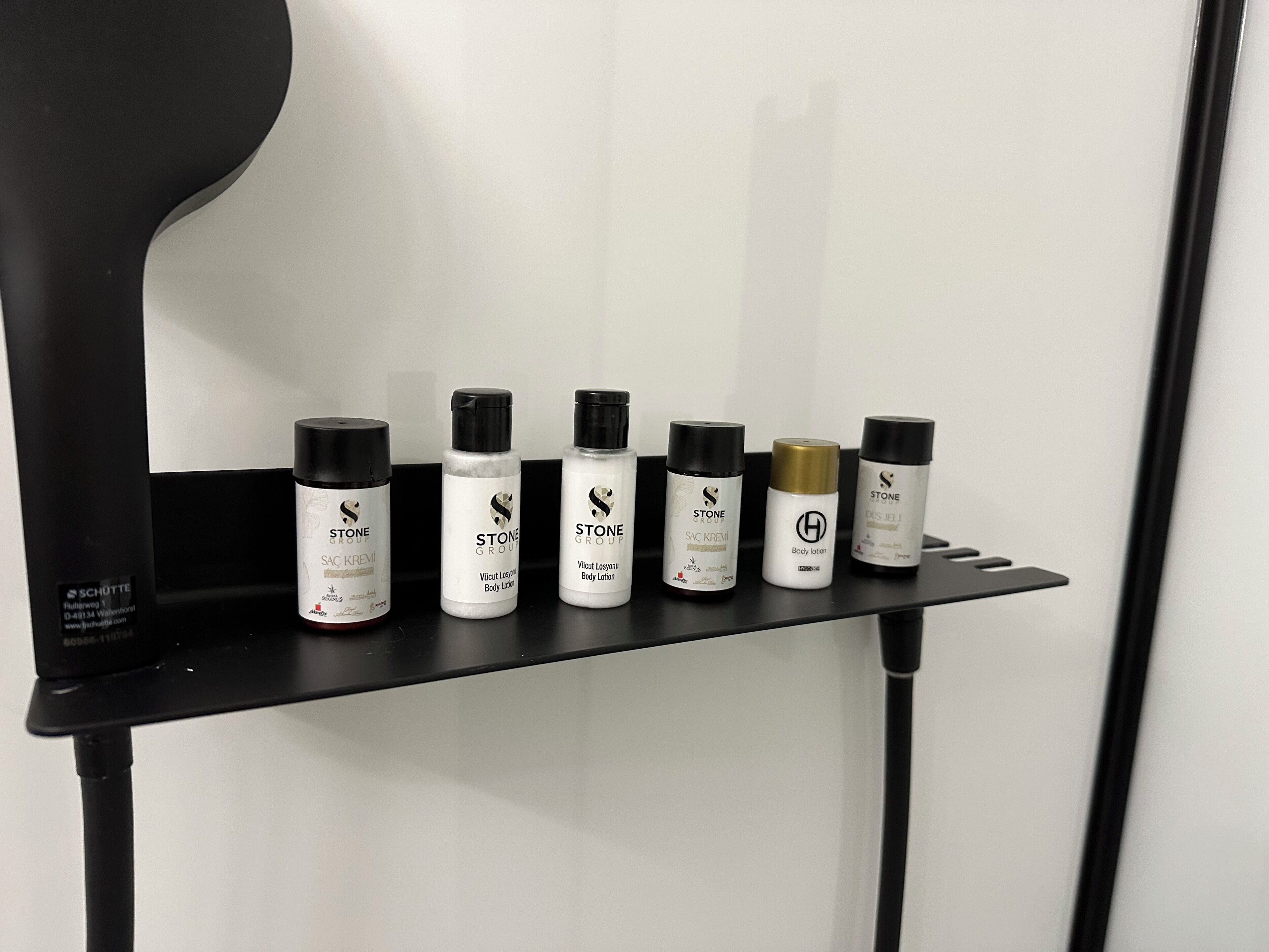 A black shelf with six bottles of Stone Group body care products.