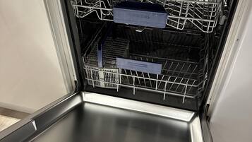 An open dishwasher with a stainless steel interior and a control panel.