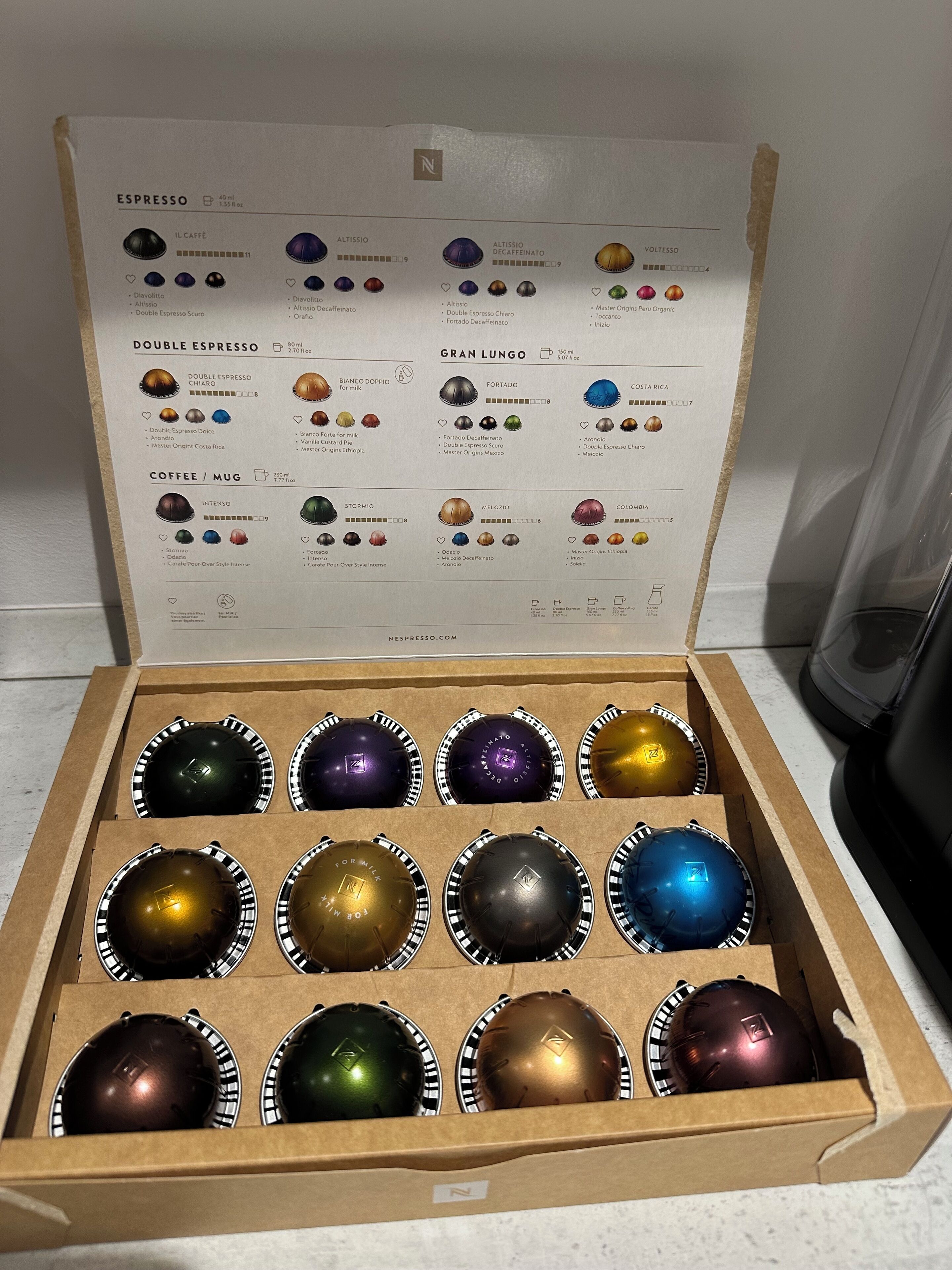 A box of Nespresso coffee capsules with a variety of flavors and origins.