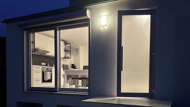 A modern house with a glass door leading to a kitchen and dining area.