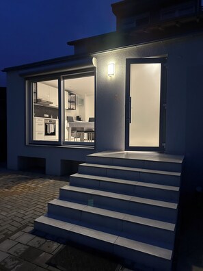 A modern house with a glass door leading to a kitchen and dining area. - Vacation apartment Guesthouse Merzig Vacation  (Merzig)