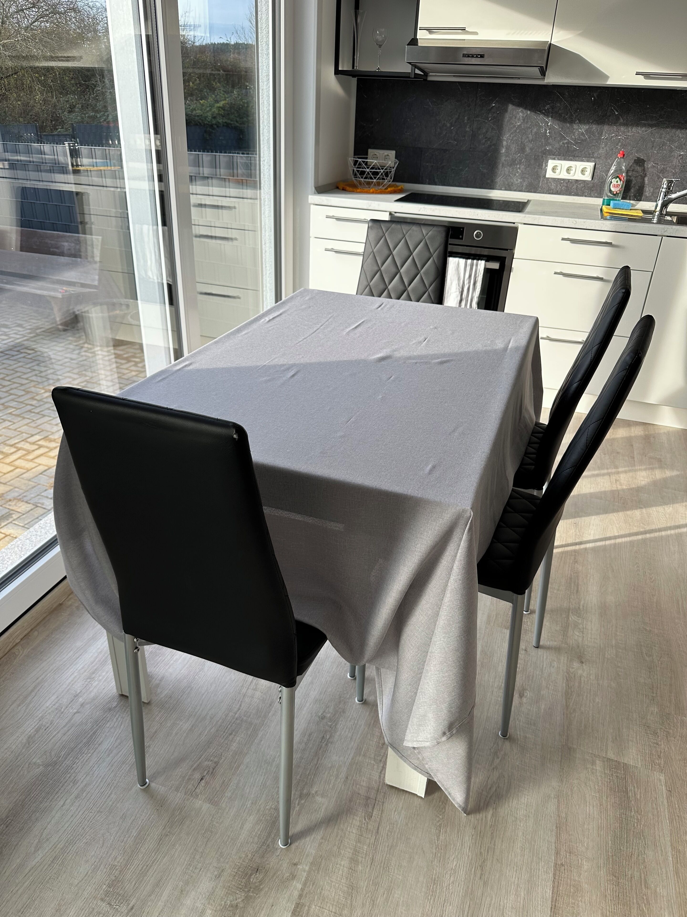 Moderni keittiö, jossa on ruokapöytä, tuolit ja suuri ikkuna, josta on näkymä.