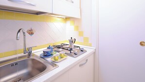 A kitchen with a stainless steel sink, a gas stove, and a yellow and white tiled backsplash.