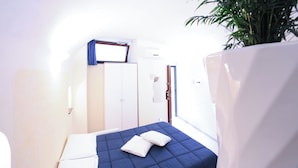 A compact bedroom with a single bed, a wardrobe, and a potted plant.