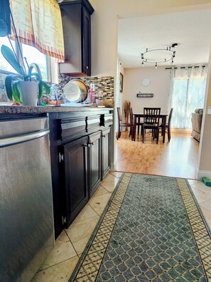 Une cuisine équipée d’un plan de travail, de placards, d’un coin repas avec des chaises, d’un tapis et d’un ventilateur de plafond.