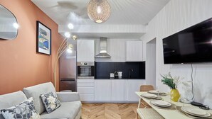 A modern living room with a sofa, coffee table, and a dining area with a table set for four. - Charming new Flat in the Centre of Paris (Paris)