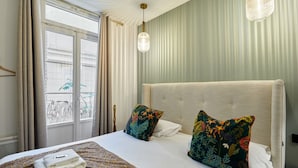 Ein Hotelzimmer mit einem großen Bett, zwei Zierkissen, einer Hängelampe und Blick auf Fahrräder vor dem Fenster.