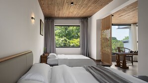 A modern hotel room with a wooden ceiling, two beds, a large window with curtains, a dining area with a table and chairs, and a view of greenery outside. - Castle peak yard Inn Guilin (Guilin)