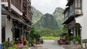 A traditional building with a balcony, a mountain backdrop, and a parked motorcycle. - Castle peak yard Inn Guilin (Guilin)