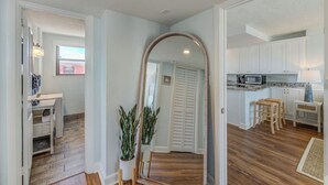 A spacious living area with a wooden floor, a large mirror, and a potted plant. - Exquisite Rooftop Deck Beach View Pool Spacious (St. Pete Beach)