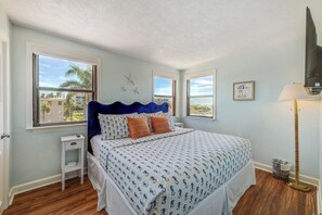 A bedroom with a bed, two windows, a nightstand, a lamp, and a starfish decoration.