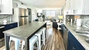 A modern kitchen with a central island, stainless steel appliances, and a dining area with a sofa and coffee table.