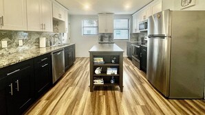 A modern kitchen with dark cabinets, a central island, and stainless steel appliances.