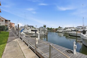Un port de plaisance avec des bateaux amarrés, une promenade en bois et un ciel dégagé.