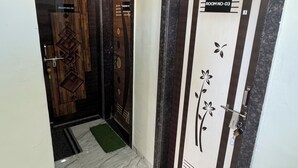 Un couloir avec deux portes, l’une portant l’inscription « CHAMBRE N° 01 » et l’autre « CHAMBRE N° 03 ». Le couloir est doté d’un sol en marbre et d’un petit tapis vert placé près des portes.