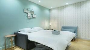 Une chambre à coucher moderne avec un grand lit, une table de chevet et un luminaire fixé au mur.