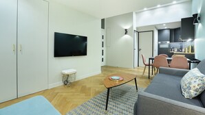 Un salon moderne doté d’un téléviseur à écran plat, d’un canapé, d’une table basse et d’un coin repas avec des chaises et une table.