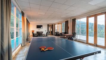Relax in this spacious room with a ping pong table and large windows offering a view of the outdoors.