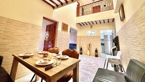 A dining area with a wooden table set for four, a kitchen in the background, and a balcony with a wrought iron railing. - Authentic Riad Dar Adam / Splendid Rooftop & Pool (Marrakech)