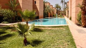 A swimming pool surrounded by palm trees and a building with a flat roof. - Authentic Riad Dar Adam / Splendid Rooftop & Pool (Marrakech)