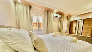A hotel room with a large bed, curtains, an air conditioning unit, and a window with a view. - Authentic Riad Dar Adam / Splendid Rooftop & Pool (Marrakech)