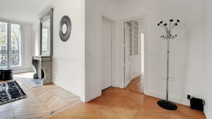 Una camera spaziosa con pavimento in legno, camino, un grande specchio e una lampada da terra alta.