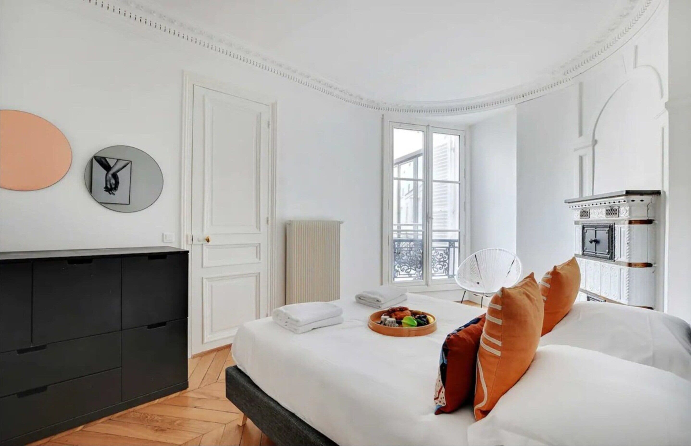 Een slaapkamer met een bed, nachtkastje, radiator, raam en een aan de muur bevestigde televisie.
