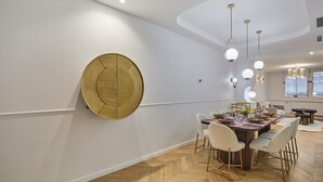 A modern dining area with a herringbone wood floor, a round gold accent wall, and a dining table set for six with white chairs. - Apartment With AC Saint-germain des Pres / Rennes (Paris)