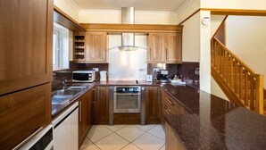 A compact kitchen with wooden cabinets, a stainless steel range hood, a built-in microwave, and a dishwasher.