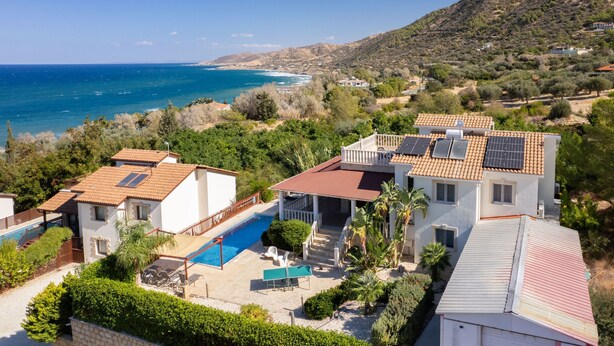 A coastal property with a swimming pool, solar panels, and a view of the sea.