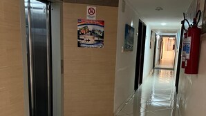 A hotel hallway with a tiled floor, a fire extinguisher, and a door with a sign. - Hotel orla Guest House (Petrolina)
