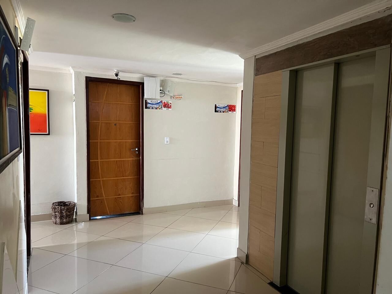 A hallway with a wooden door, a tiled floor, and a wall-mounted air conditioning unit.
