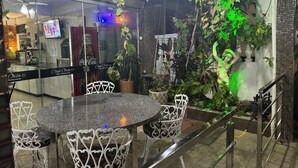 A restaurant with a round table and white chairs, surrounded by potted plants and greenery. - Hotel orla Guest House (Petrolina)