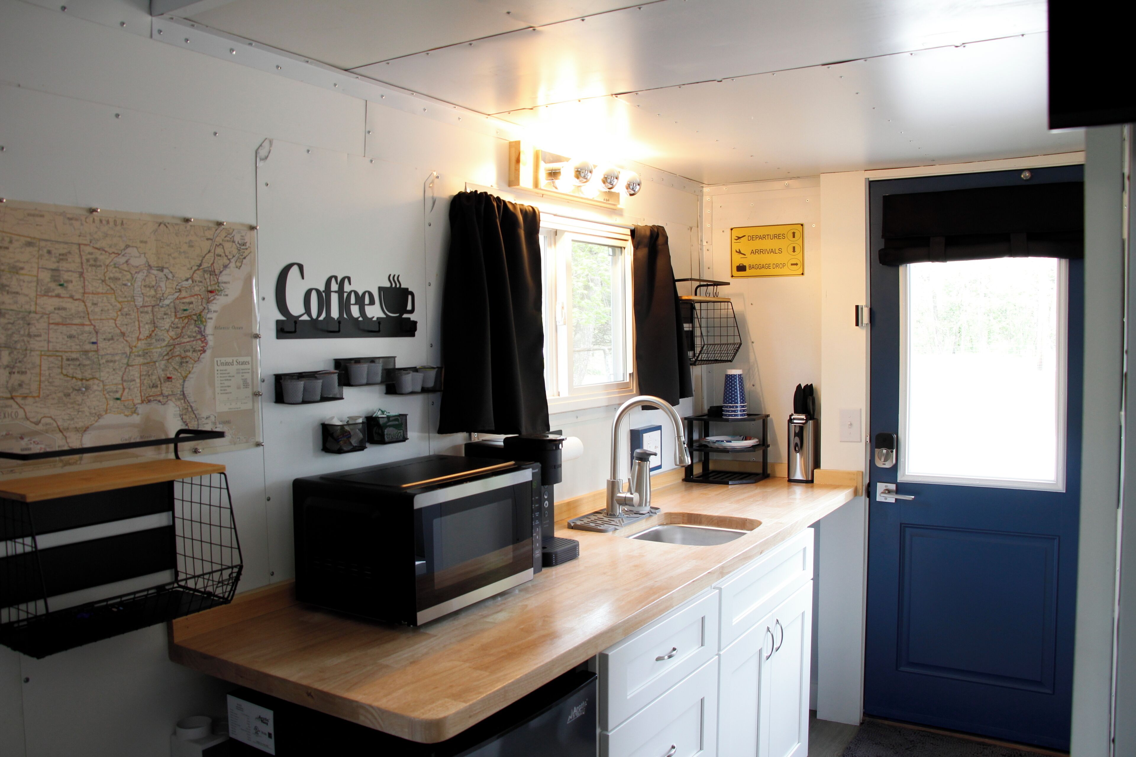 A kitchen with a map, coffee station, and a blue door.
