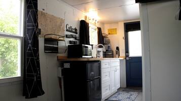A compact kitchen with a refrigerator, microwave, coffee machine, and a small sink.
